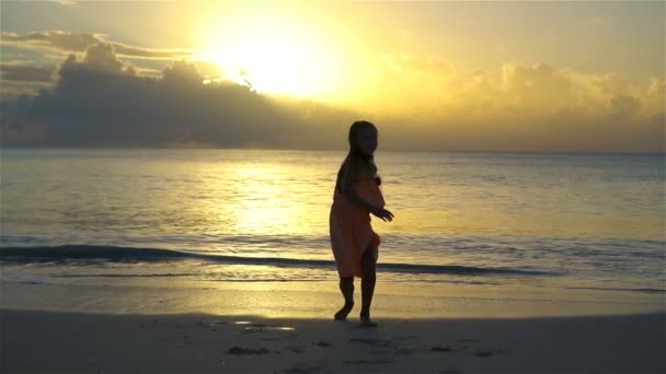 Adorabile bambina felice hanno un sacco di divertimento sulla spiaggia bianca al tramonto. SLOW MOTION — Video Stock