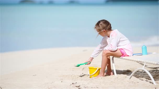 Чарівна маленька дівчинка грає з іграшками на пляжі. Дитина грає з піском на сонячному ліжку — стокове відео