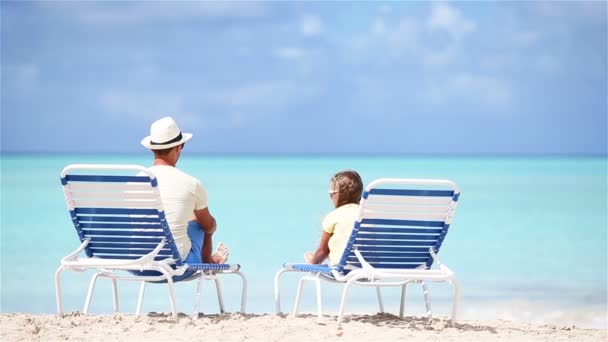 Vader en dochter handen omhoog op strand zittend op chaise-longue — Stockvideo