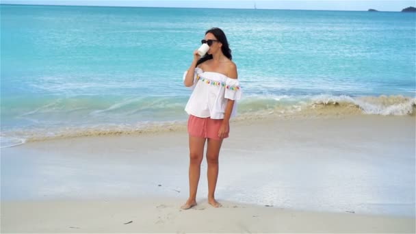 Mujer joven con café caliente en la playa tropical blanca. MOCIÓN LENTA — Vídeo de stock