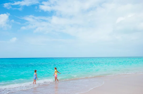 Szczęśliwy dziewczynki w płytkiej wodzie, na plaży, mając mnóstwo zabawy — Zdjęcie stockowe
