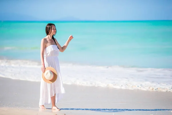在白色海滩的帽子的年轻快乐的妇女乐趣 — 图库照片