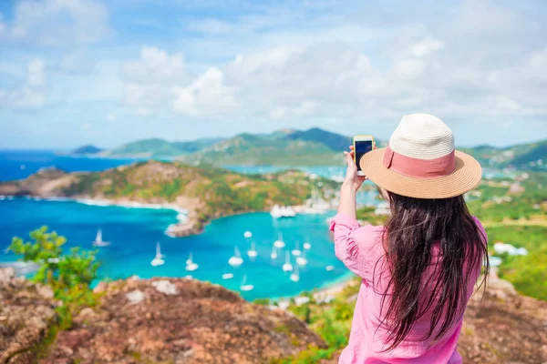 Young tourist woman making photo of English Harbor from Shirley Heights, Antigua, paradise bay at tropical island in the Caribbean Sea — Stock Photo, Image