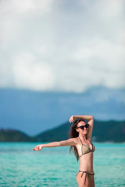 Νεαρή γυναίκα απολαμβάνοντας τον ήλιο κάνοντας ηλιοθεραπεία στην παραλία με λευκή — Φωτογραφία Αρχείου
