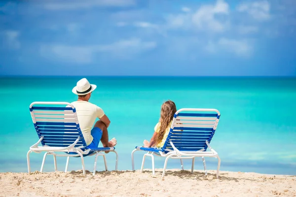 Padre e figlia mani in alto sulla spiaggia seduti sulla chaise-longue — Foto Stock