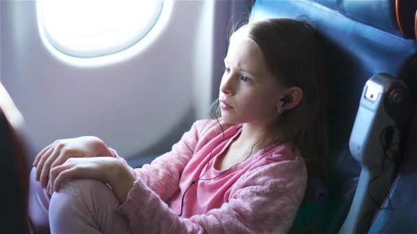 Entzückendes kleines Mädchen, das mit dem Flugzeug reist. Niedliches Kind sitzt in Flugzeugfenster — Stockvideo