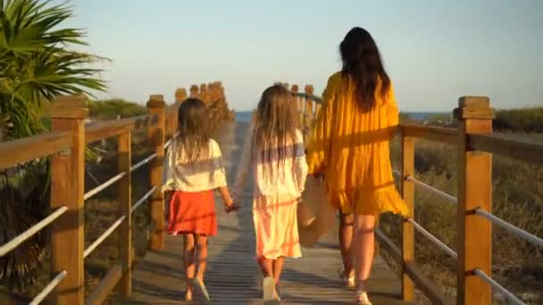 Adorable little girls and young mother walking on white beach in the evening — Stock Video