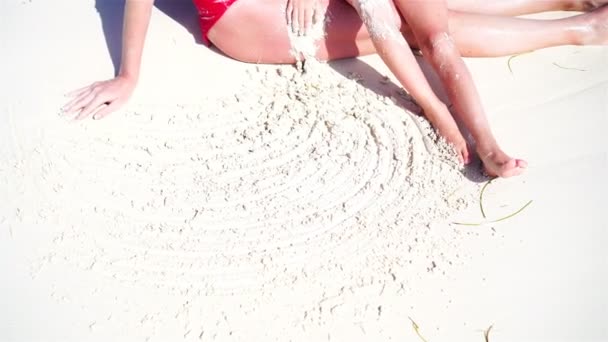 Gros plan des pieds de la mère et de l'enfant assis en eau peu profonde sur la plage — Video