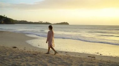 Sevimli mutlu küçük kız beyaz kumsalda akşam yürüyüş