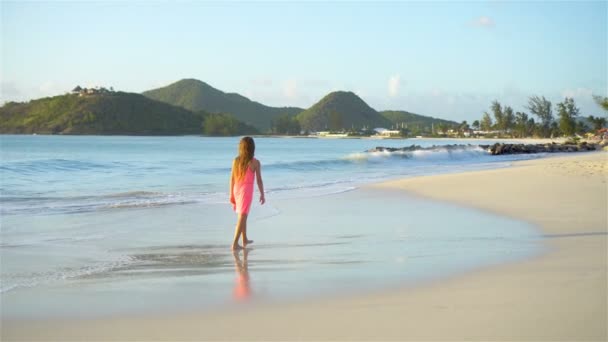 Чарівна щаслива маленька дівчинка на білому пляжі, що гуляє і насолоджується відпусткою — стокове відео