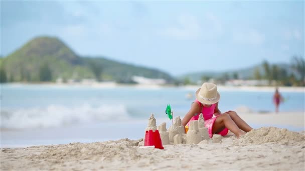 Чарівна маленька дівчинка грає з іграшками на пляжі — стокове відео
