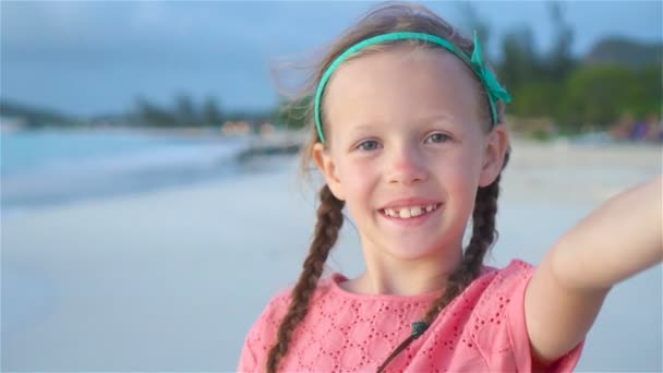 Adorable niñita tomando selfie en la playa tropical blanca. MOCIÓN LENTA — Vídeos de Stock