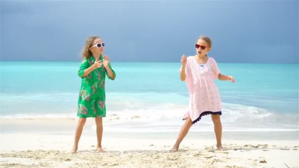 Adorables niñas tienen un montón de diversión en la playa. Dos hermosos niños bailando en la orilla del mar — Vídeos de Stock