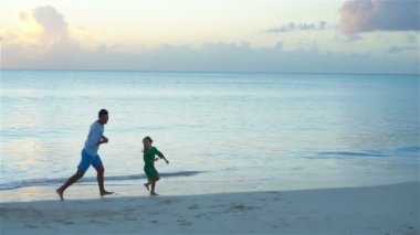 Mutlu bir aile birlikte sahilde oynarken. Baba ve Karayipler tatil günlerinde çalışan çocuklar. Ağır çekim