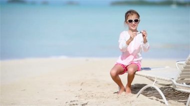 Beyaz kumlu sahilde elinde oyuncak uçakla küçük mutlu bir kız. Çocuk kumsalda oyuncakla oynuyor.