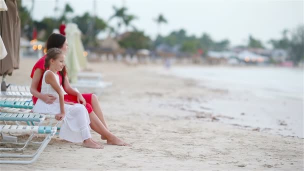 Familjen till mamma och barn njuta av havsutsikt på vit strand. Familj avkopplande sitter på solarium tittar på vackra färgglada solnedgång — Stockvideo