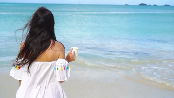 Mladá žena s horkou kávou na tropické pláži s bílým. Zpomalený pohyb — Stock video