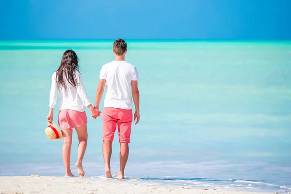 Молодая пара, гуляющая по тропическому пляжу с белым песком и бирюзовой морской водой на острове Антигуа в Карибском море — стоковое фото