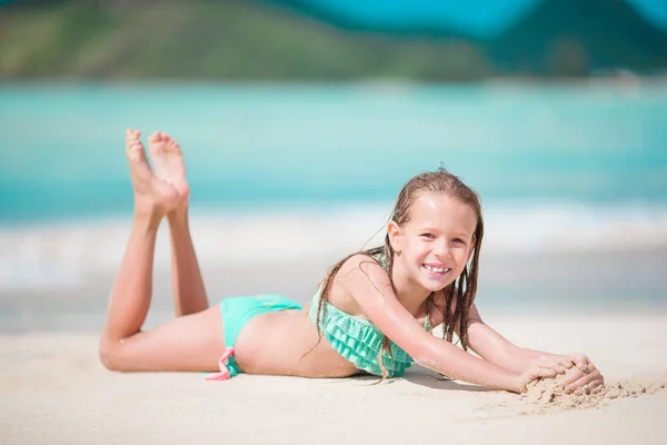 Liebenswertes kleines Mädchen am Strand, das viel Spaß im seichten Wasser hat — Stockfoto