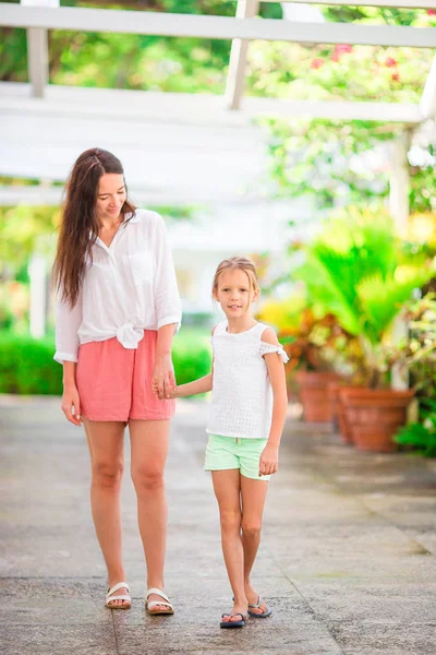 Маленькая девочка и мама, гуляющие в роскошном курорте на летних каникулах — стоковое фото