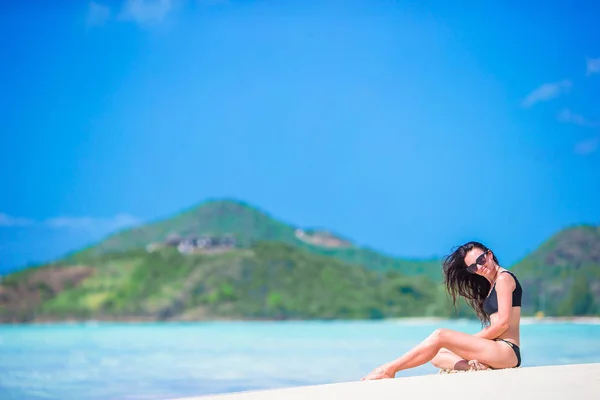 Gülüyor ve yaz tatili kameraya bakarak zevk sahilde oturan kadın. Oturarak bikinili güzel model. — Stok fotoğraf