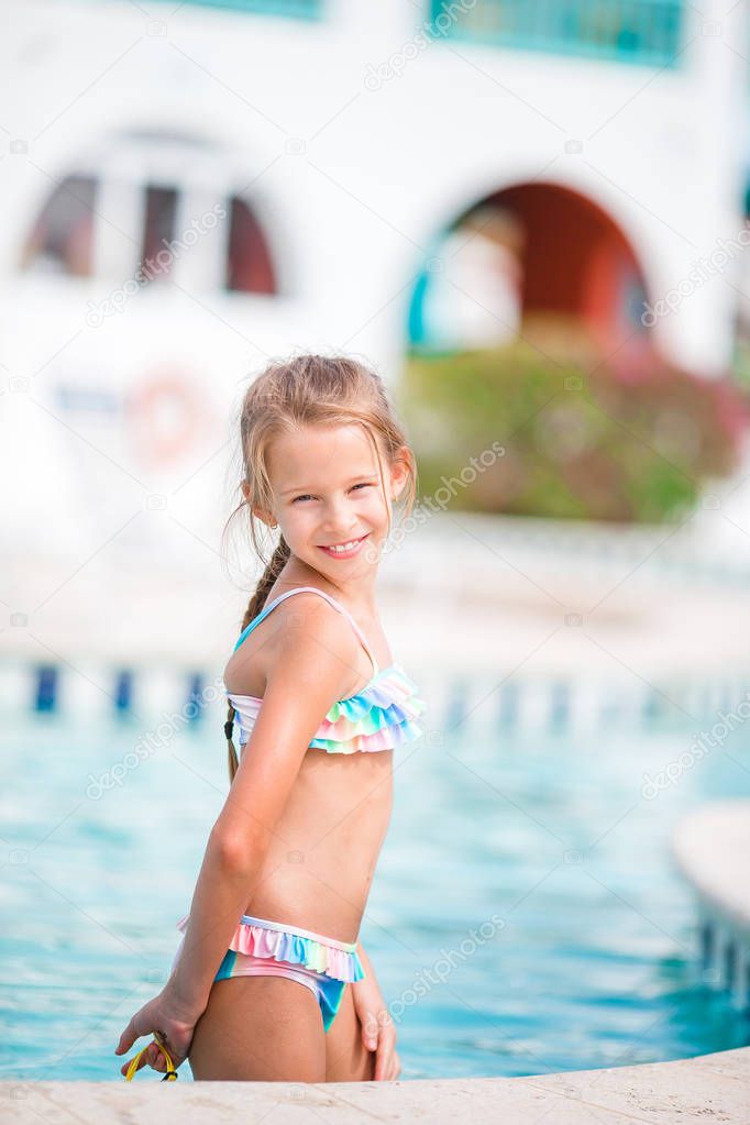 Adorable little girl relaxing at outdoor swimming pool
