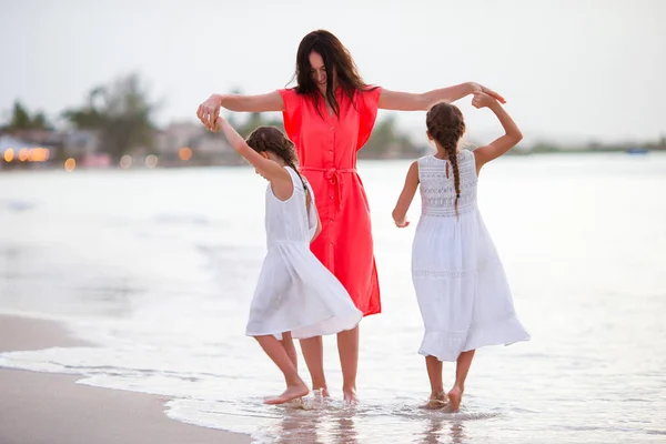 Beautiful mother and her adorable little daughters on the beach — Stock Photo, Image