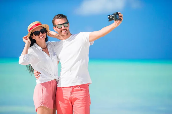 Счастливая пара делает селфи на белом пляже. Два взрослых человека наслаждаются отдыхом на тропическом экзотическом пляже — стоковое фото