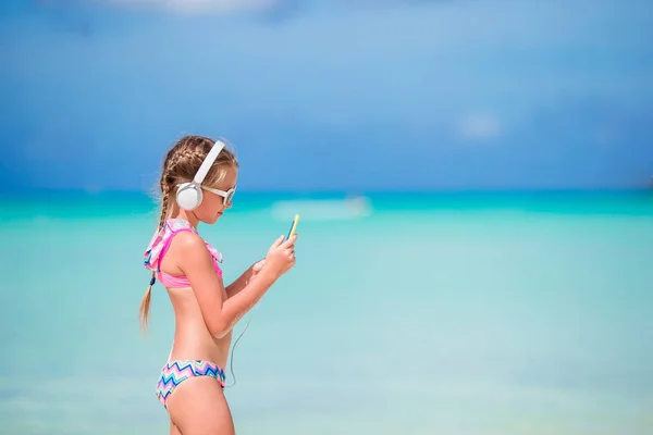 Niña con auriculares en la playa — Foto de Stock