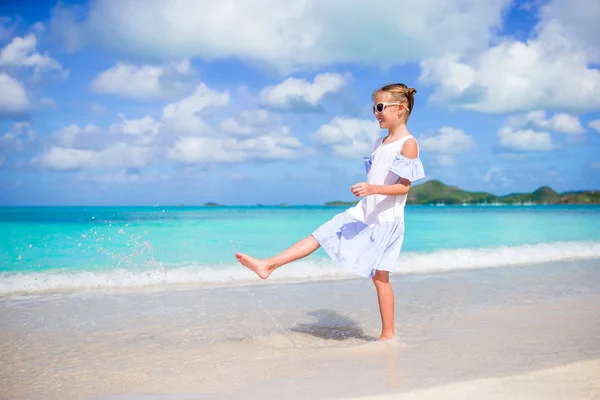 Kumsaldaki sevimli küçük kız. Mutlu kız yaz tatilinin tadını çıkar Mavi gökyüzü ve denizdeki turkuaz su — Stok fotoğraf