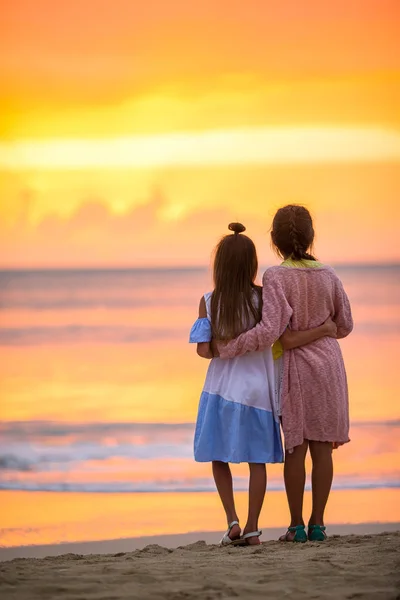 Adorable little girls on the beach with beautiful colorful sunset — Stock Photo, Image
