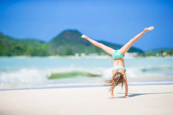 Beautiful little girl doing sporty exercises on the beach — Stock Photo, Image