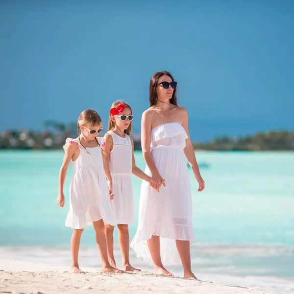 Beautiful mother and her adorable little daughters on the beach — Stock Photo, Image