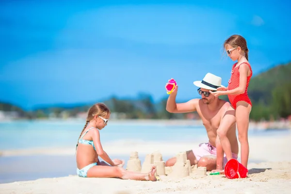 Tropikal beyaz Beach aile yapma Kumdan kale. Baba ve iki kız tropik sahilde kum ile oynamak — Stok fotoğraf