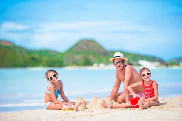 Tropikal beyaz Beach aile yapma Kumdan kale. Baba ve iki kız tropik sahilde kum ile oynamak — Stok fotoğraf