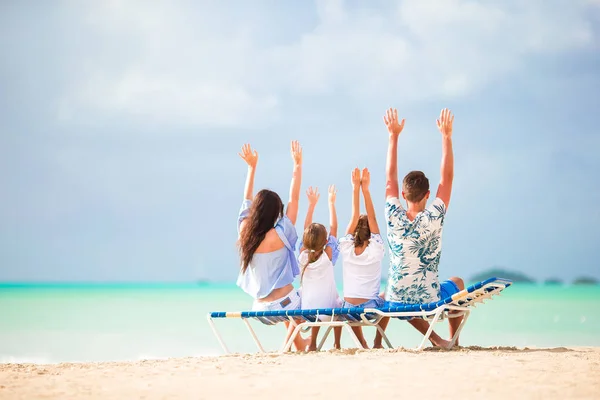 Gelukkig mooi familie op het strand. Achteraanzicht van ouders en kinderen op de chaise-lounge — Stockfoto