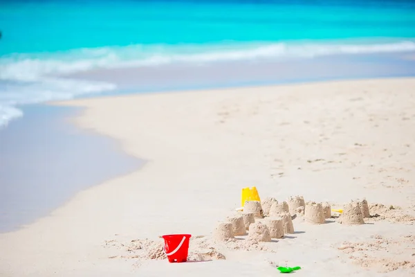 Zandkasteel op wit tropisch strand met plastic kinderspeelgoed — Stockfoto