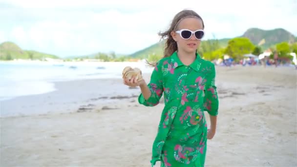 Roztomilá holčička s mušle v rukou na tropické pláži. Rozkošná holčička hraje s mušle na pláži — Stock video