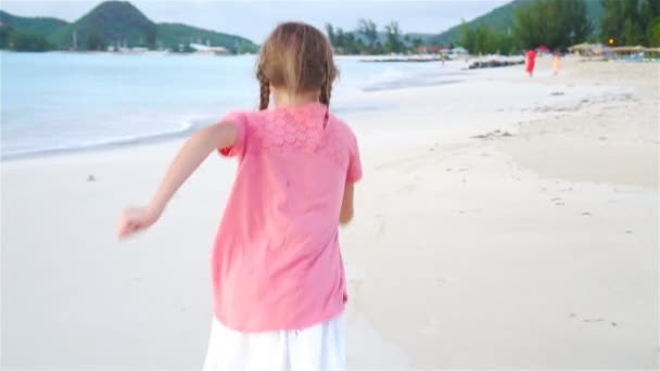 Schattig meisje draait op het strand. Gelukkig kind geniet van de zomervakantie. Slow Motion — Stockvideo