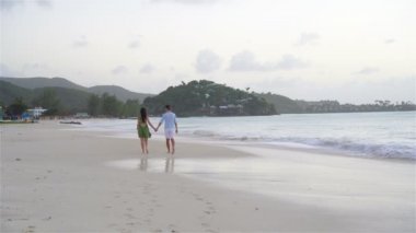 Karayipler 'deki Antigua adasında beyaz kum ve turkuaz okyanus suyuyla tropikal plajda genç bir çift.