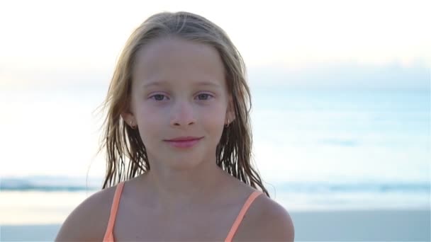 Porträt eines kleinen Mädchens, das in die Kamera schaut und vor dem Hintergrund des schönen Himmels und Meeres lächelt. Langsame Motorisierung — Stockvideo