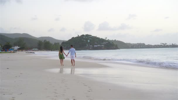 Νεαρό ζευγάρι στην τροπική παραλία με λευκή άμμο και γαλαζοπράσινα νερά στον ωκεανό στο νησί Αντίγκουα της Καραϊβικής — Αρχείο Βίντεο