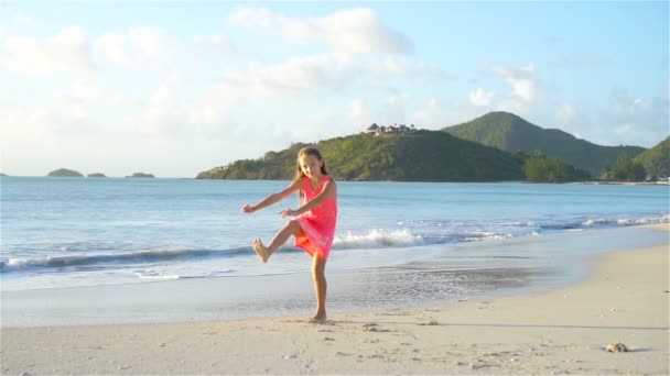 Chica activa en la playa divirtiéndose mucho. Lindo niño haciendo ejercicios deportivos en la orilla del mar — Vídeos de Stock