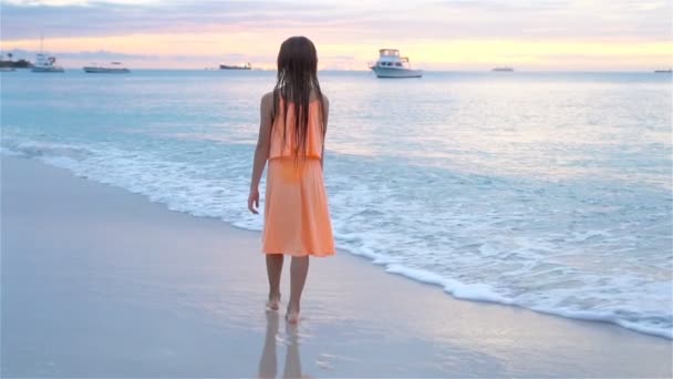 Schattig gelukkig meisje wandelend op wit strand bij zonsondergang. SLOW MOTION — Stockvideo