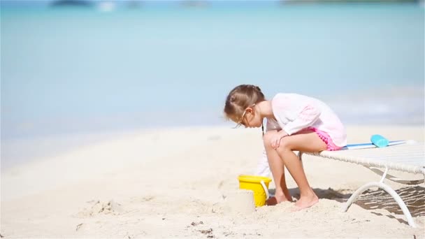 Чарівна маленька дівчинка грає з іграшками на пляжі. Дитяча гра з піском — стокове відео