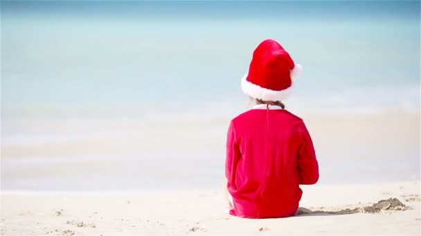 Visão traseira da menina adorável em chapéu de Natal na praia branca durante as férias de Natal — Vídeo de Stock