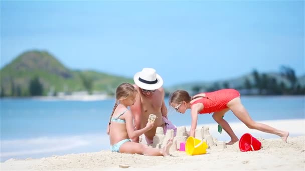 Familia haciendo castillo de arena en la playa tropical blanca. Padre y dos niñas jugando con arena en la playa tropical — Vídeos de Stock