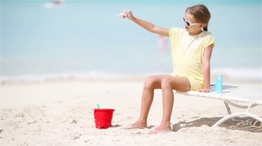 Beyaz kumlu sahilde elinde oyuncak uçakla küçük mutlu bir kız. Çocuk kumsalda oyuncakla oynuyor.