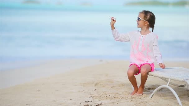 Niña feliz con avión de juguete en las manos en la playa de arena blanca. Niño jugar con juguete en la playa — Vídeo de stock