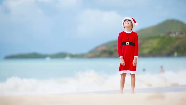 Little adorable girl in Christmas hat on white beach during Xmas vacation — Stock Video